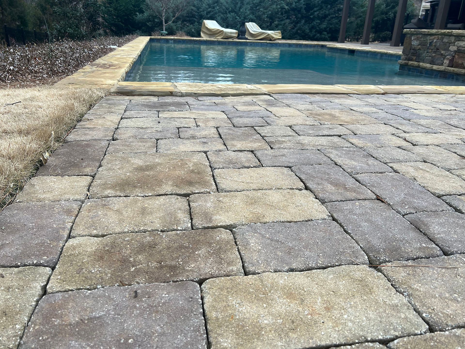 A brick walkway leading to a large swimming pool.