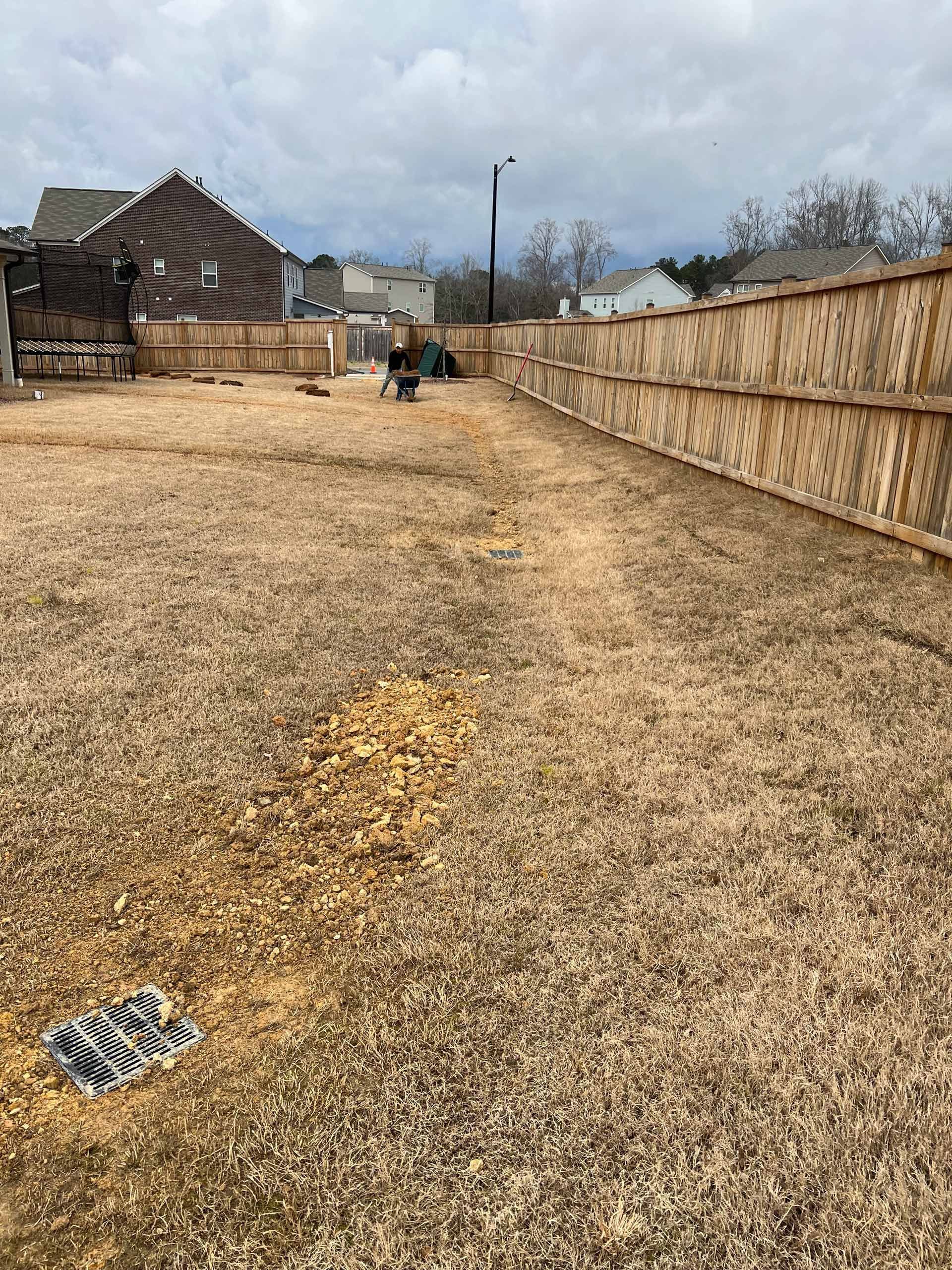 A large empty yard with a wooden fence in the background.