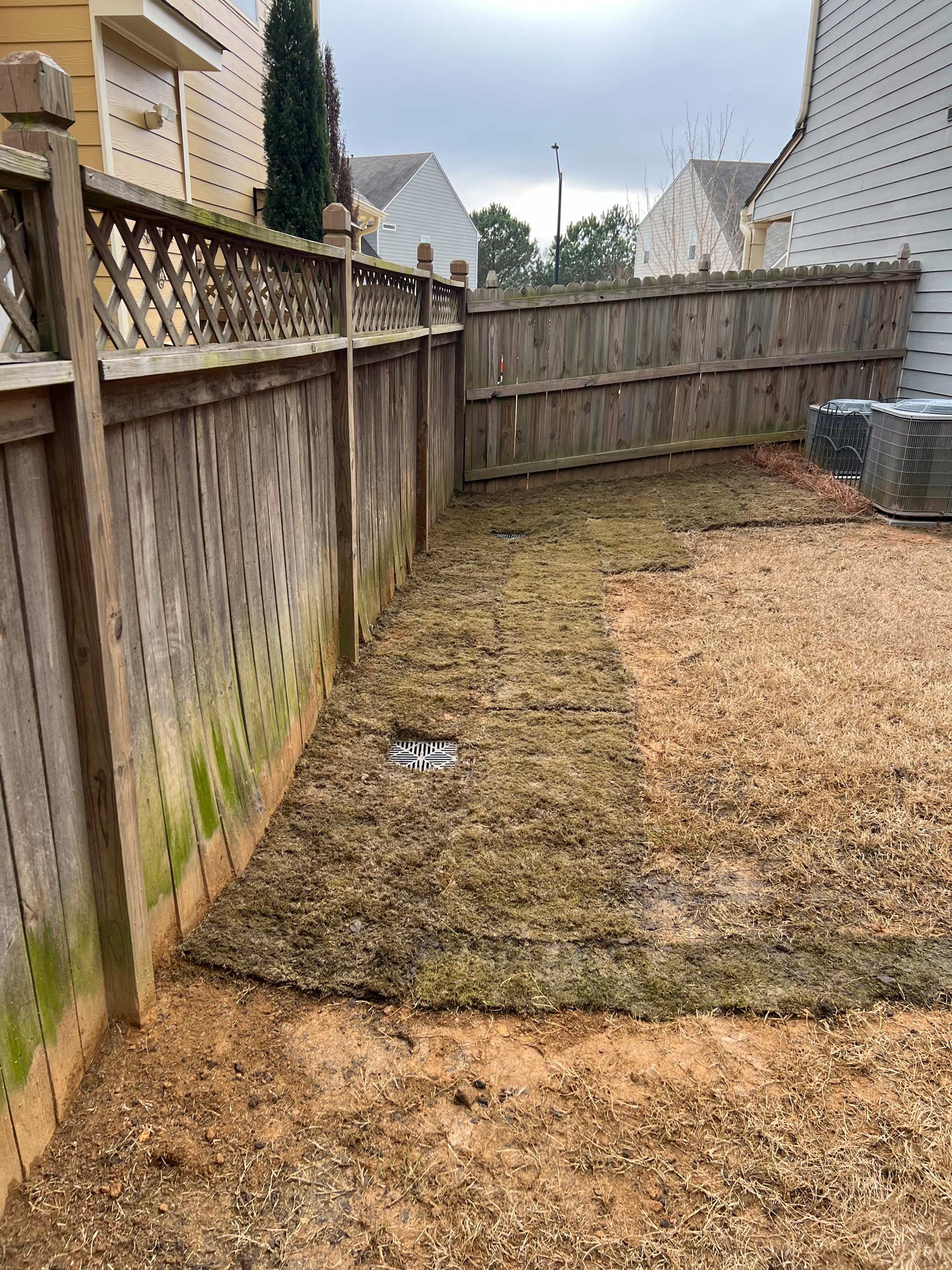 A backyard with a wooden fence and a lot of dirt.