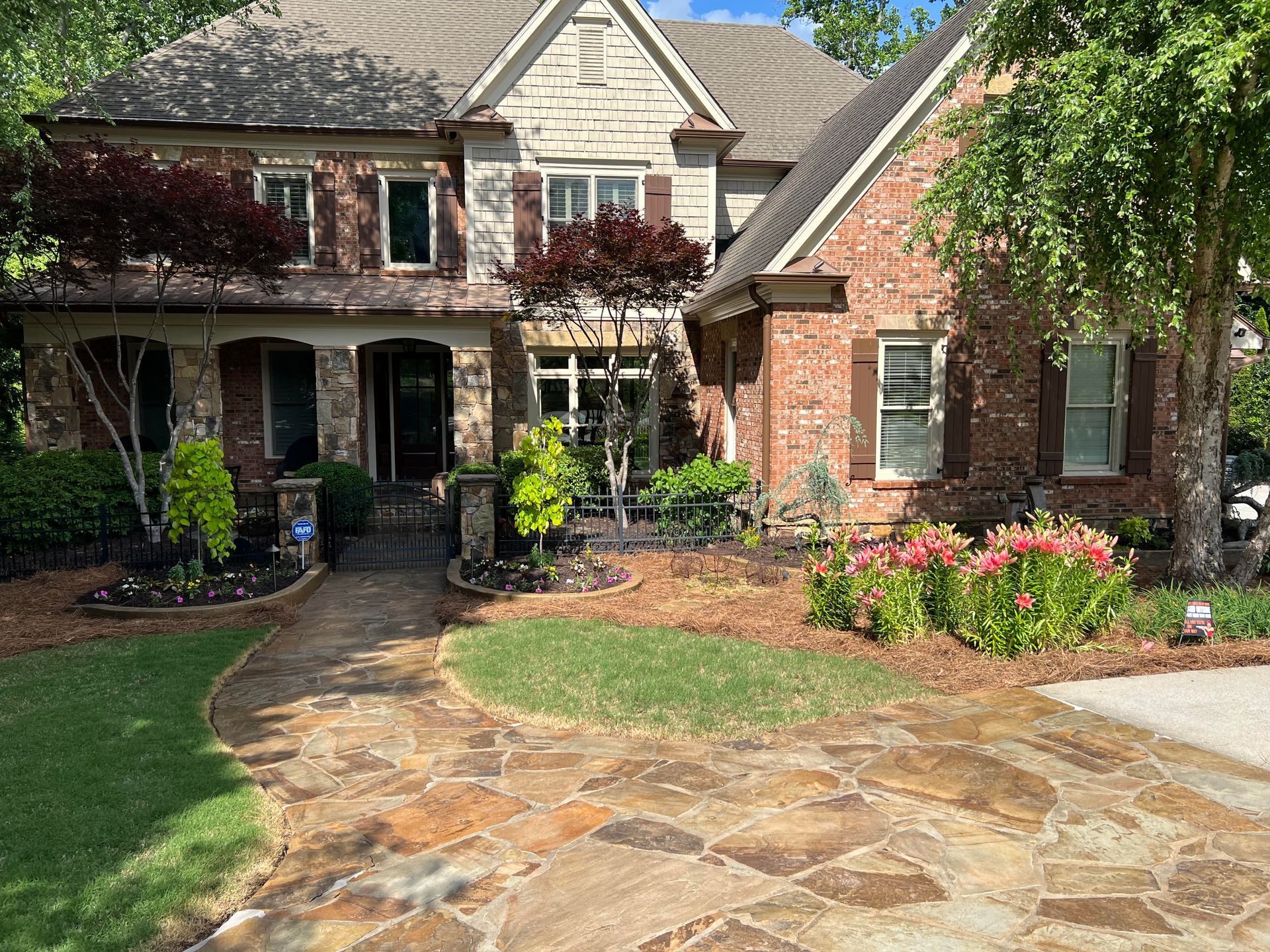A large brick house with a stone driveway in front of it.