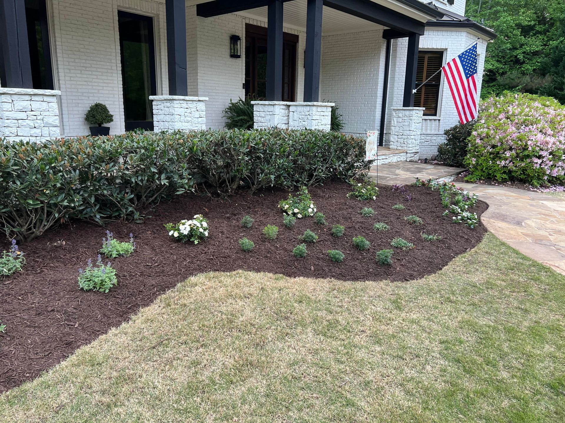A house with a flag in front of it and a lush green lawn.