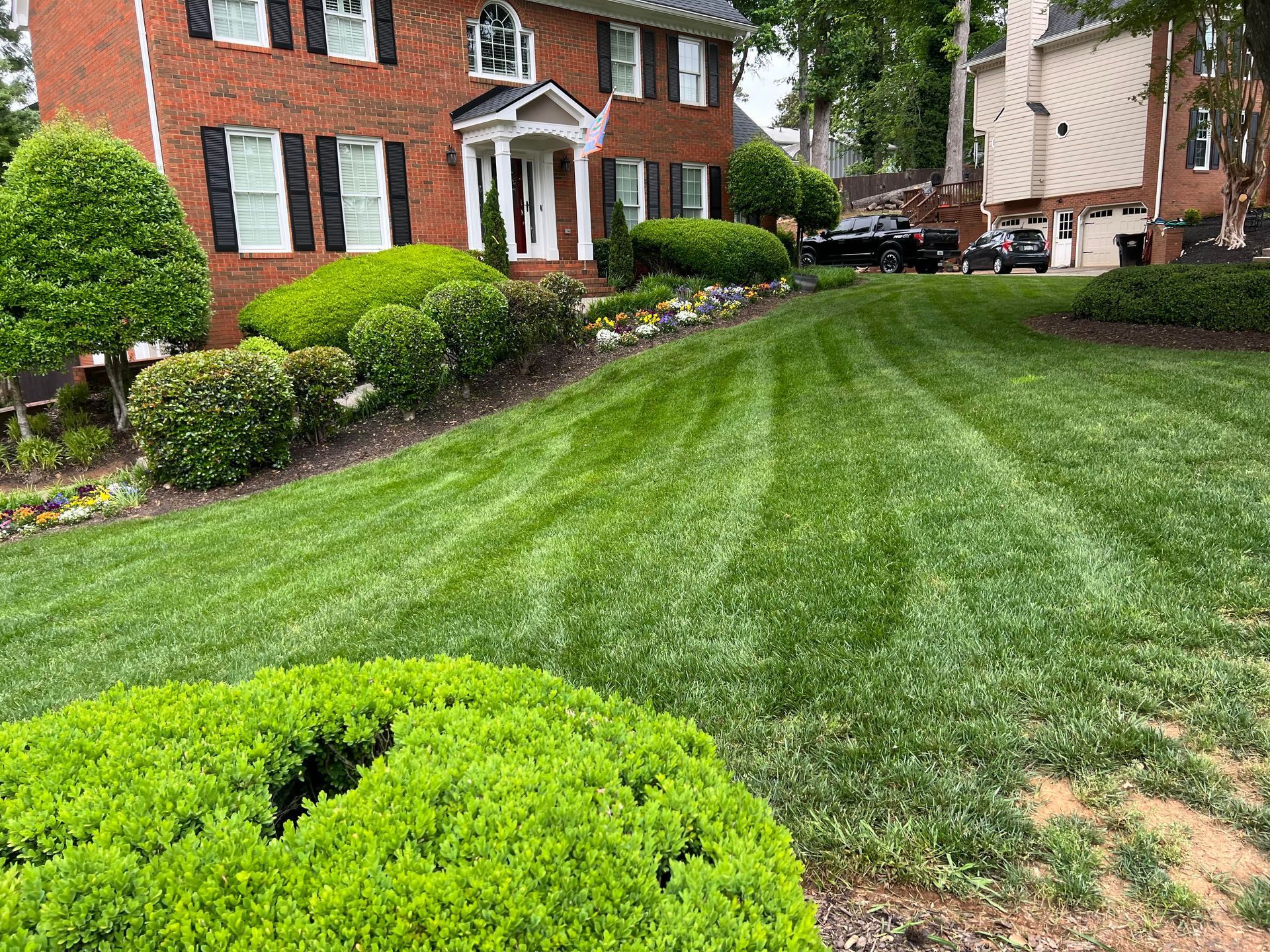 A lush green lawn in front of a brick house.