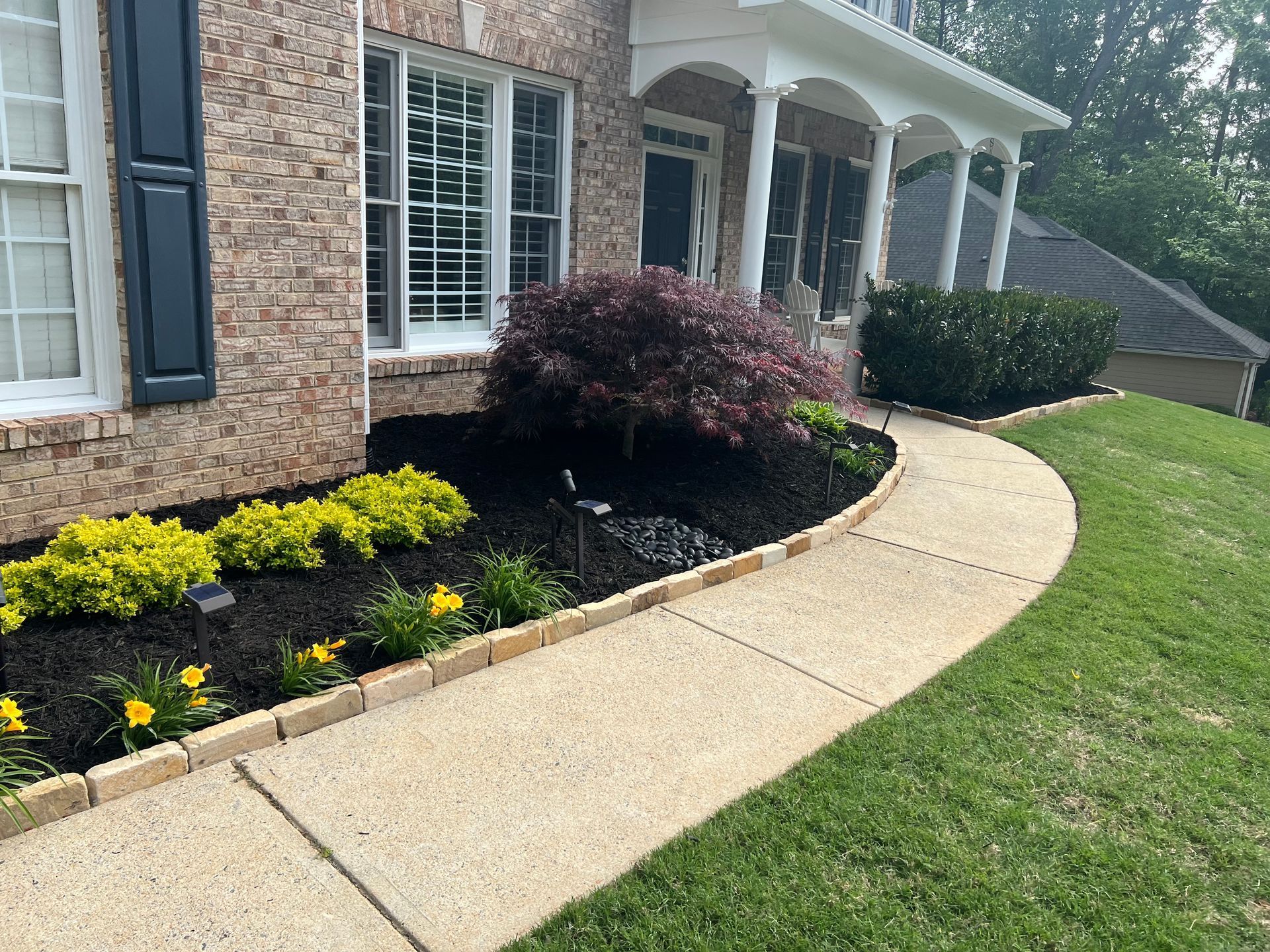 A brick house with a walkway leading to it and a lush green lawn.