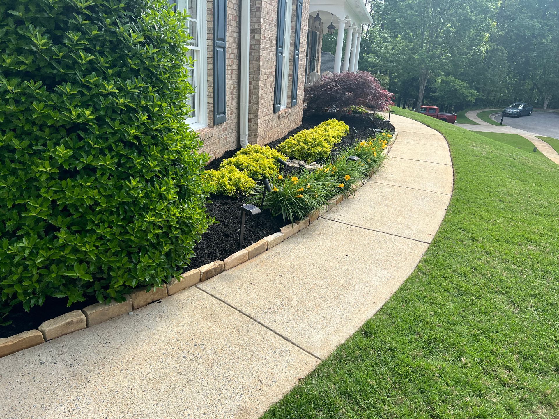 A sidewalk leading to a house with a lush green lawn.