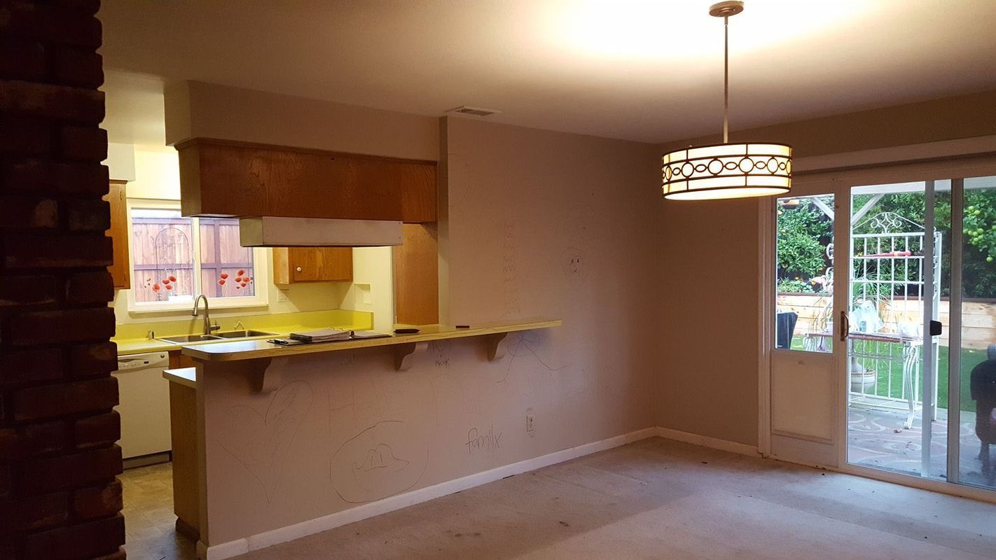 Interior view of a kitchen and dining area with a bar, sliding glass door, and a decorative light fixture.