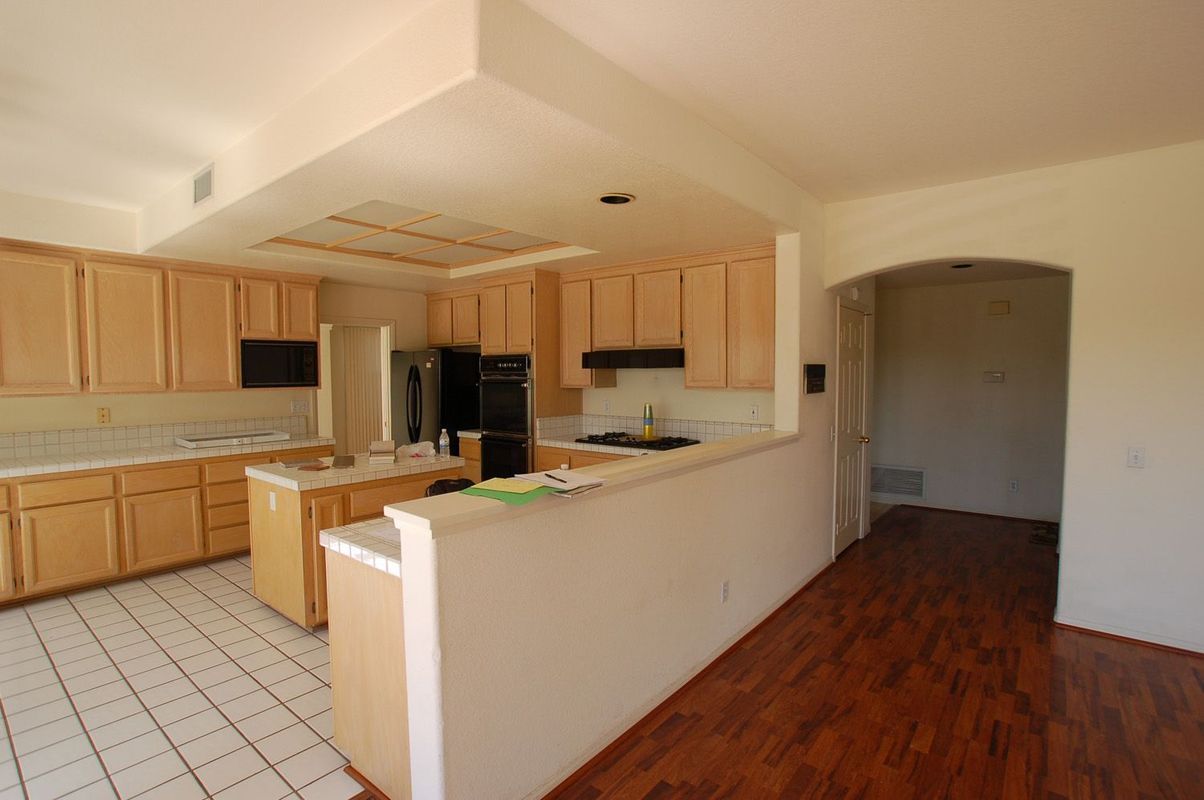 Kitchen with light wood cabinets, white countertops, and white tile flooring.