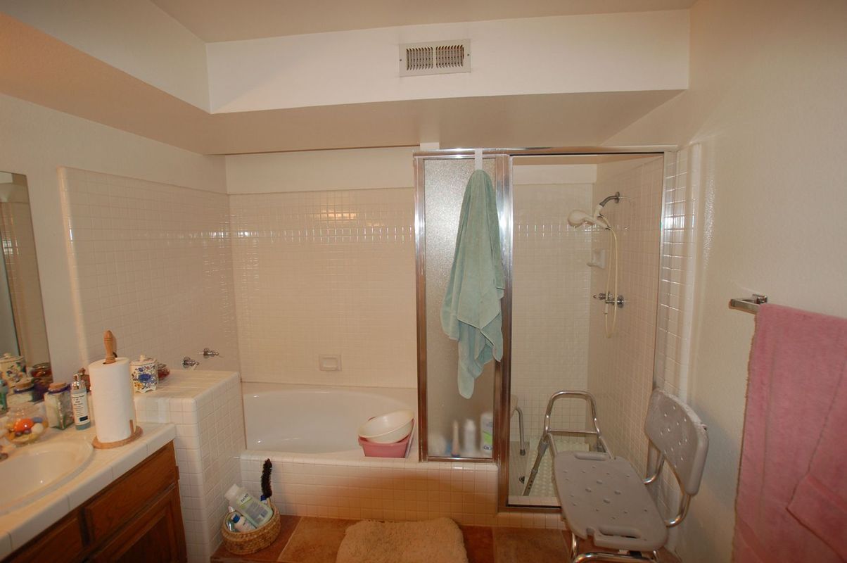 Bathroom with bathtub, shower, and safety equipment, including a transfer chair.