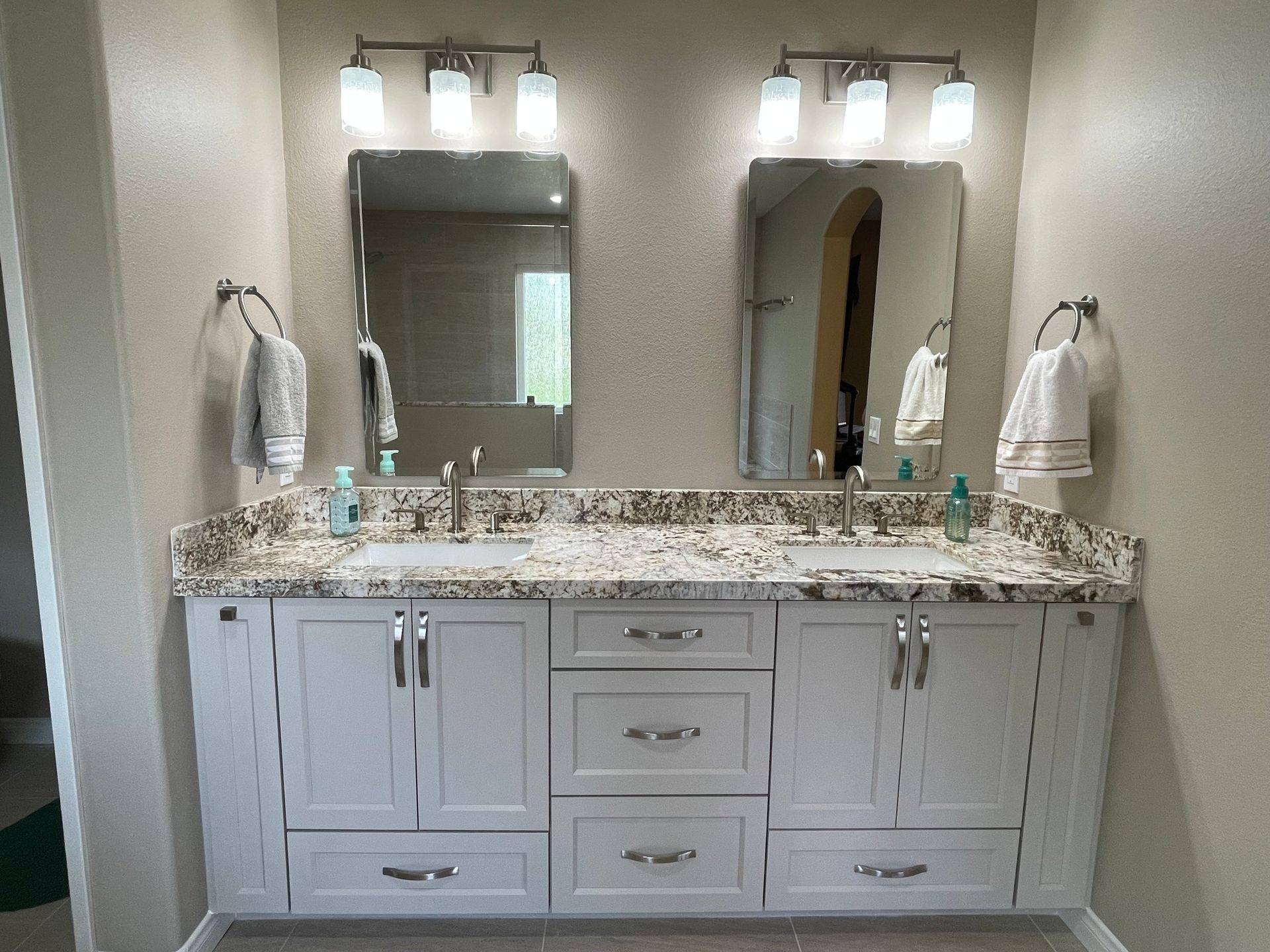 Dual sink vanity with white cabinets, granite countertop, and two mirrors.