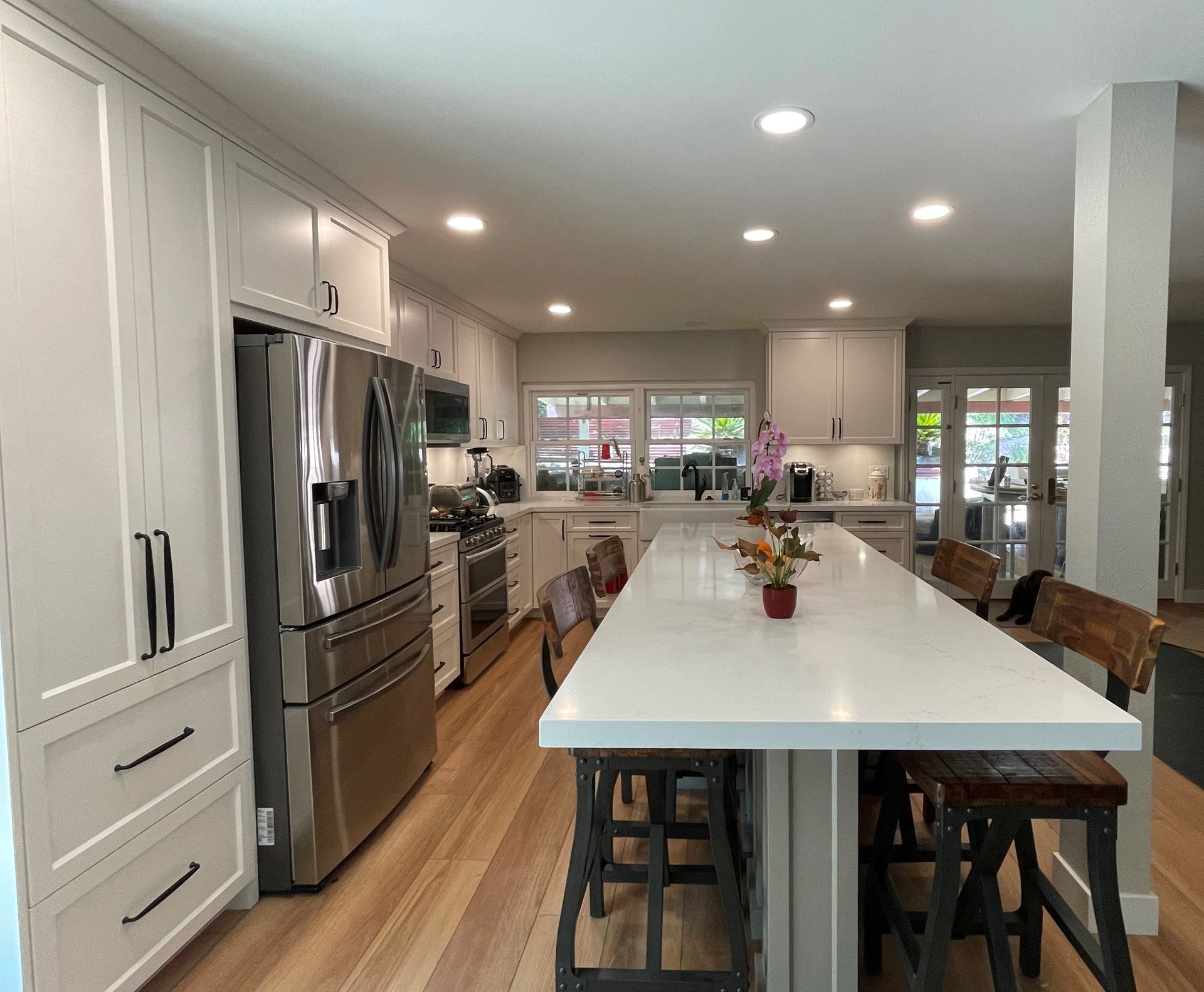 Kitchen with white cabinets, stainless steel appliances, and a long island with stools.