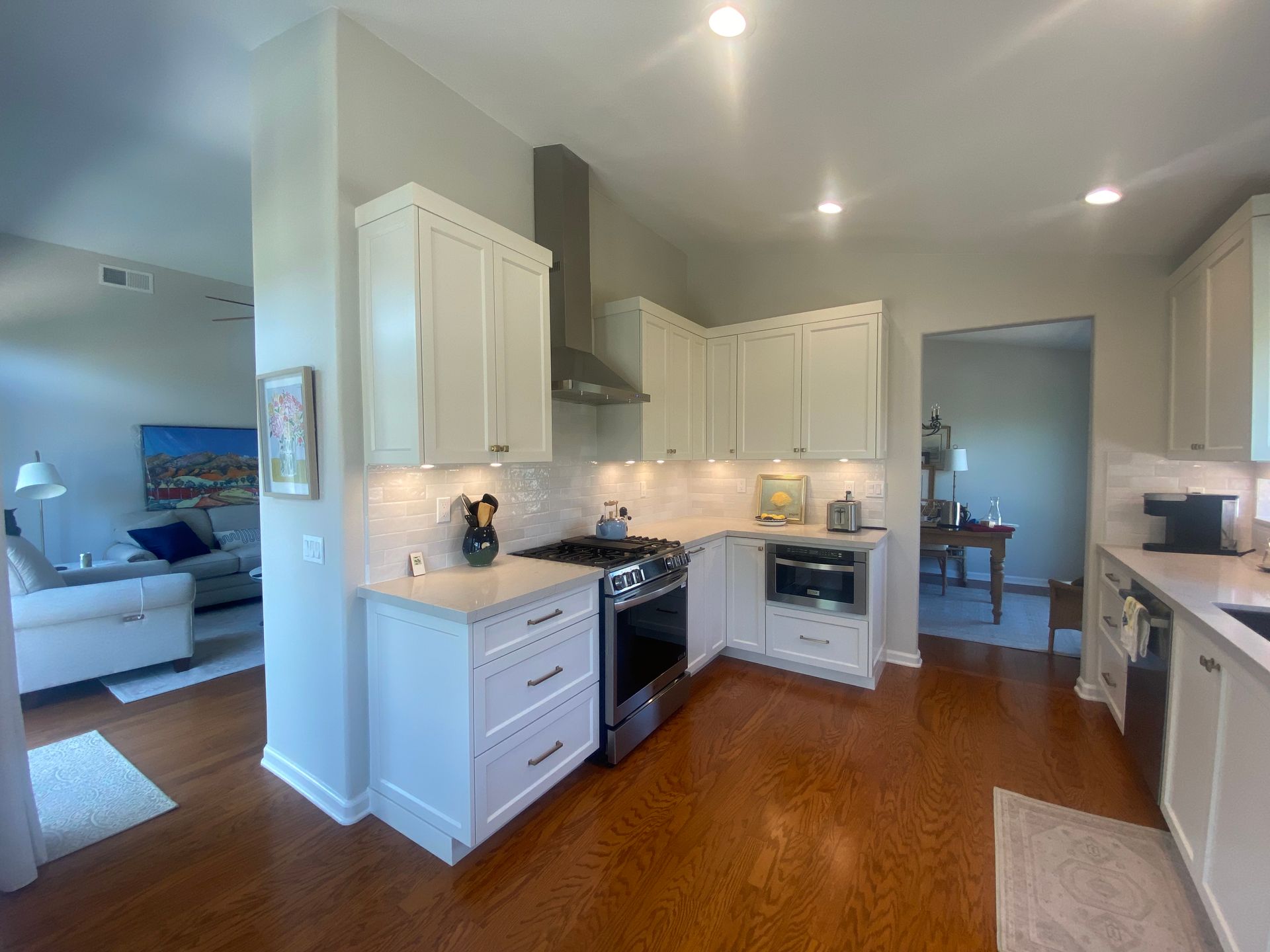 Kitchen with cream cabinets, stainless steel appliances, and wood floor; view into living room.
