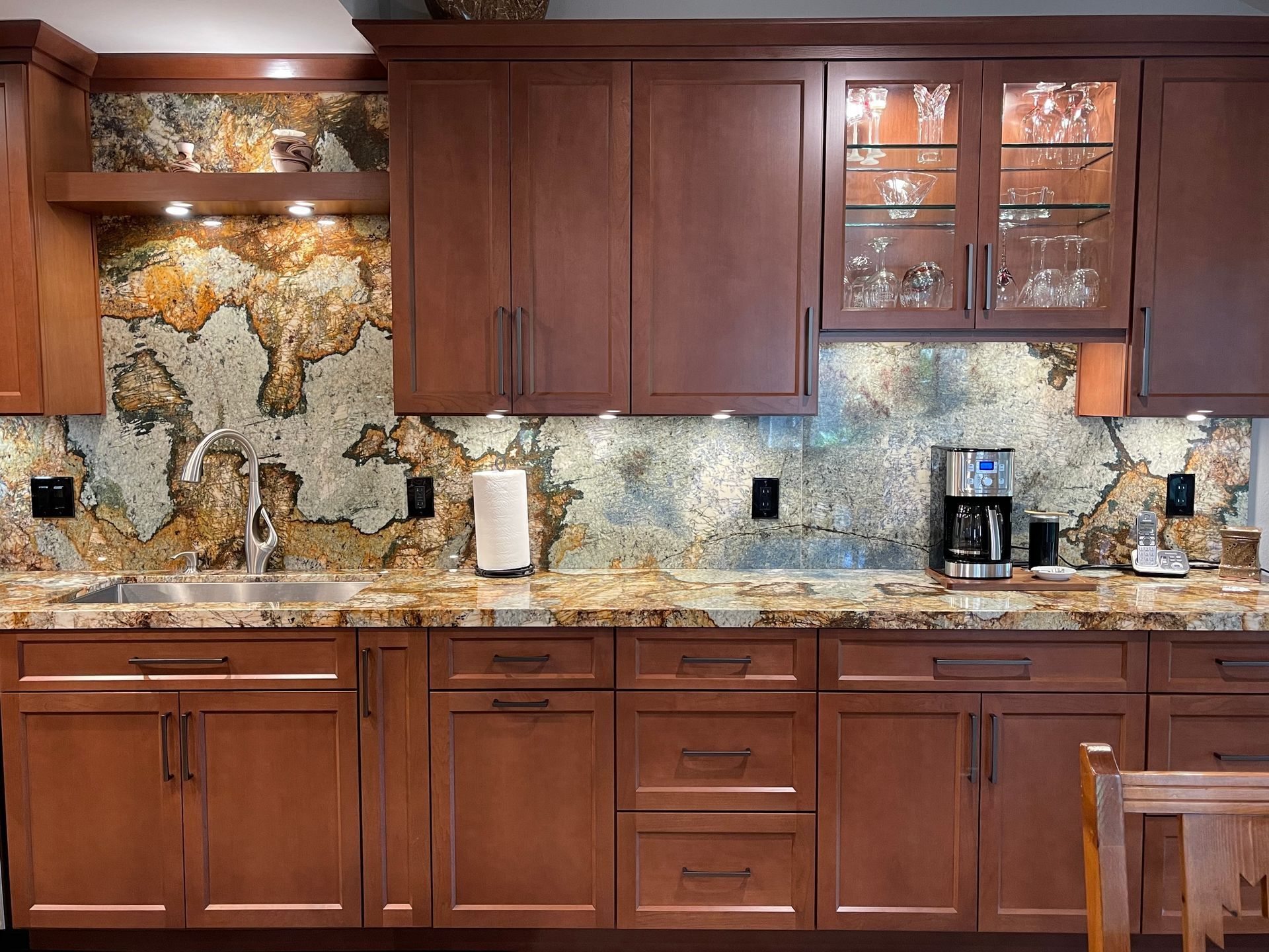 Kitchen with brown cabinets, granite countertops, and patterned backsplash.