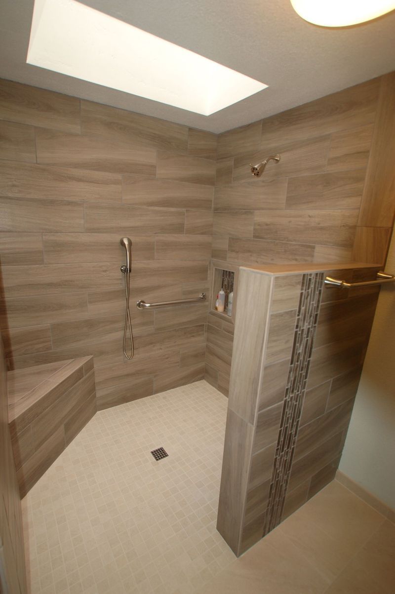 Accessible shower with brown tiled walls, bench, and contrasting floor tiles. Includes grab bar and built-in niche.