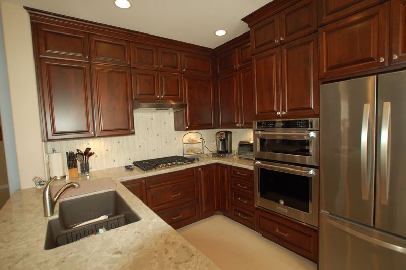 Kitchen with dark wood cabinets, stainless steel appliances, and light countertops.
