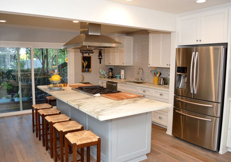 Modern kitchen with island seating, stainless steel appliances, and sliding glass doors to a patio.