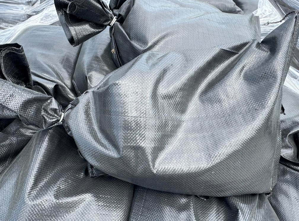 Piles of black plastic sacks or tarps bundled together on the ground