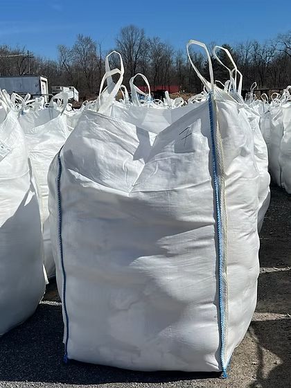 White bulk bags with blue trim lined up outdoors in a snowy field under a clear sky
