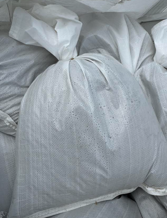 White woven sacks filled with material, tightly tied and stacked together