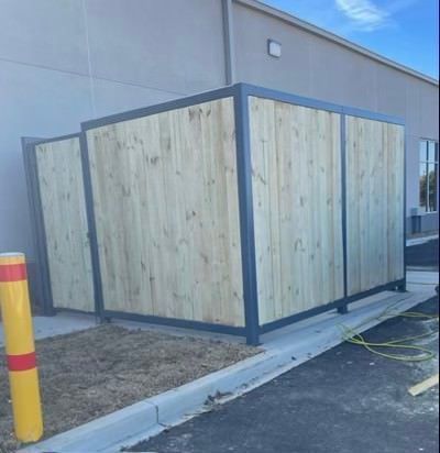 a wooden fence is sitting in front of a building .