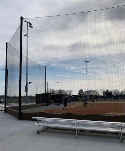 a baseball field with a fence and benches in front of it .