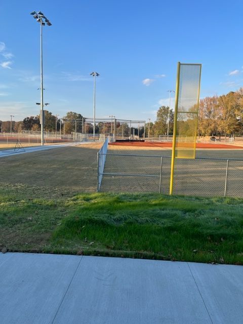 a baseball field with a fence and a few lights