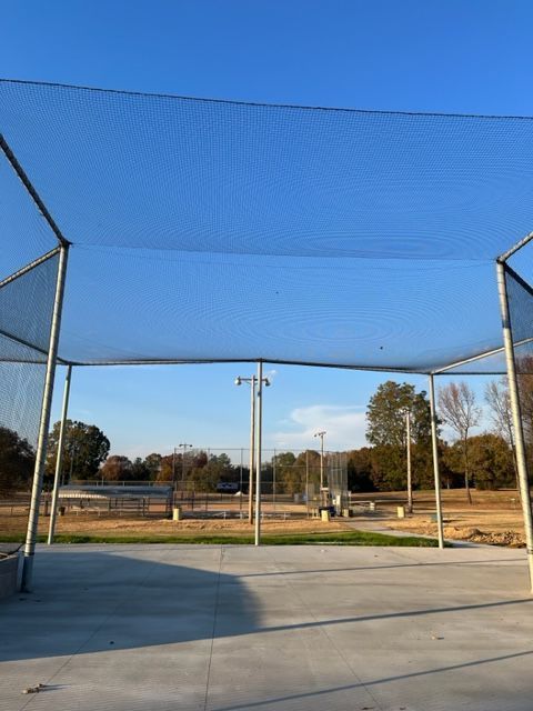 a baseball cage with a blue sky in the background