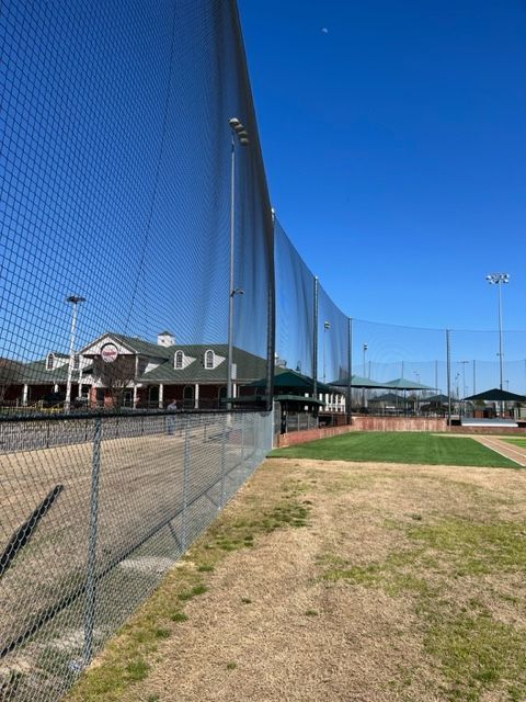 a fence surrounds a baseball field with a building in the background