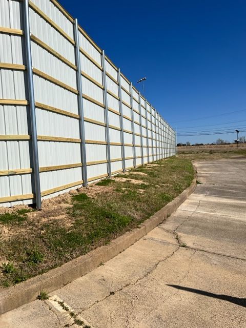 a white fence with wooden posts is next to a sidewalk