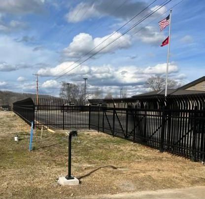 a black fence with two american flags flying in front of a building .