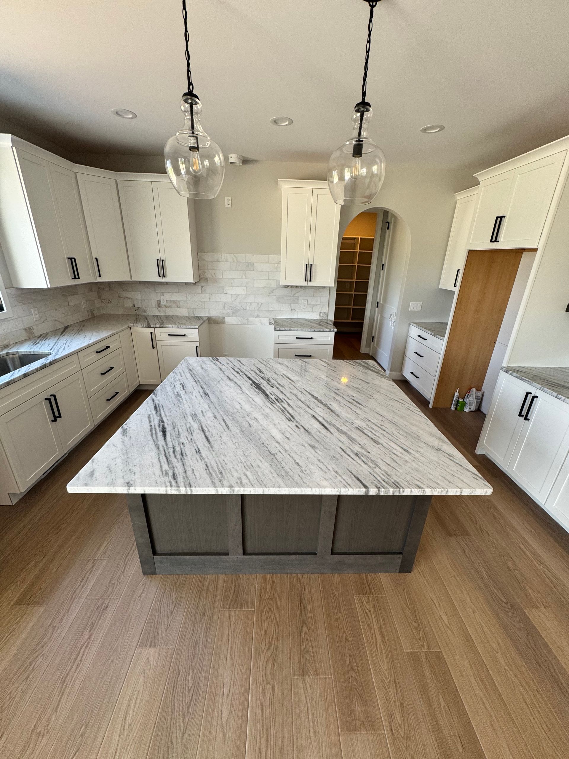 A kitchen with white cabinets and a large marble counter top.