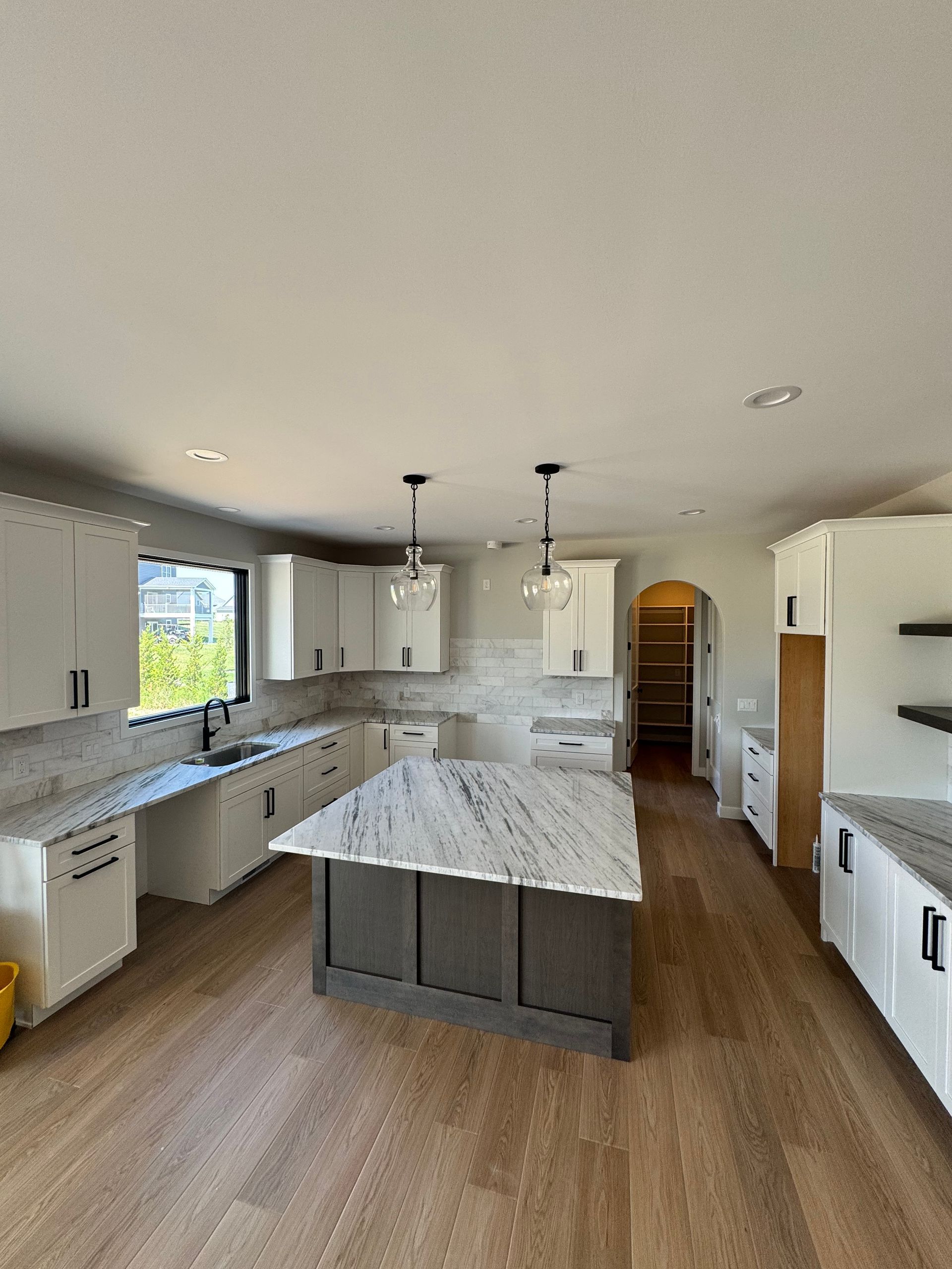 A kitchen with white cabinets and a large island in the middle.