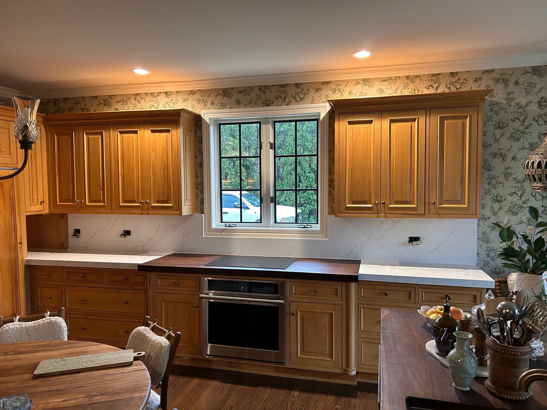 A kitchen with wooden cabinets , stainless steel appliances , and a large window.