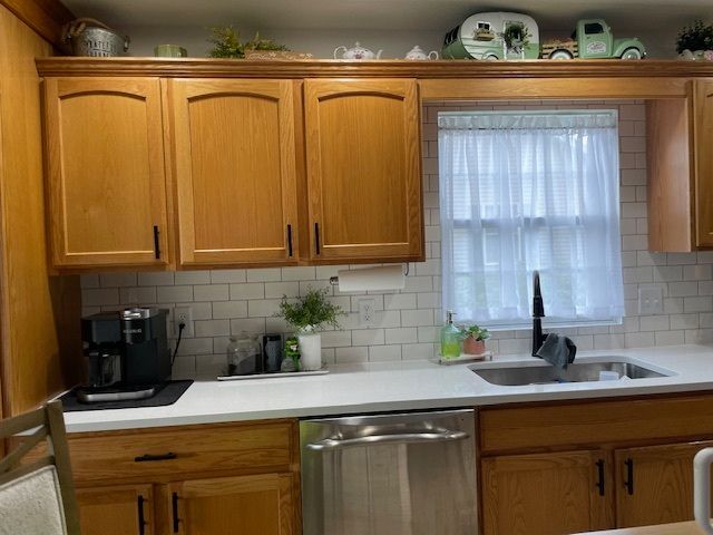 A kitchen with wooden cabinets, a sink, a dishwasher, and a window.