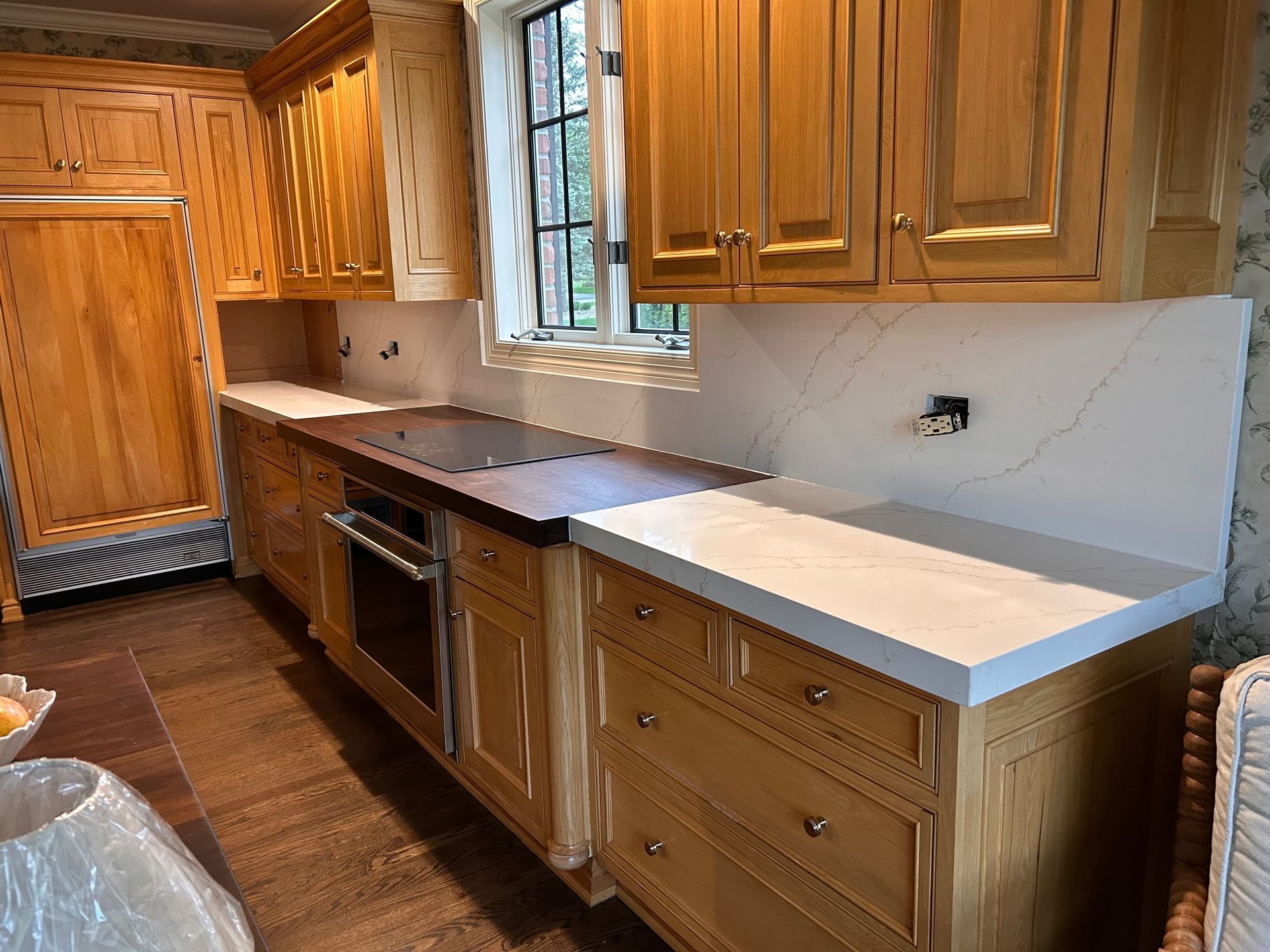 A kitchen with wooden cabinets and white counter tops.