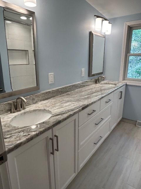 A bathroom with two sinks, two mirrors, and a window.