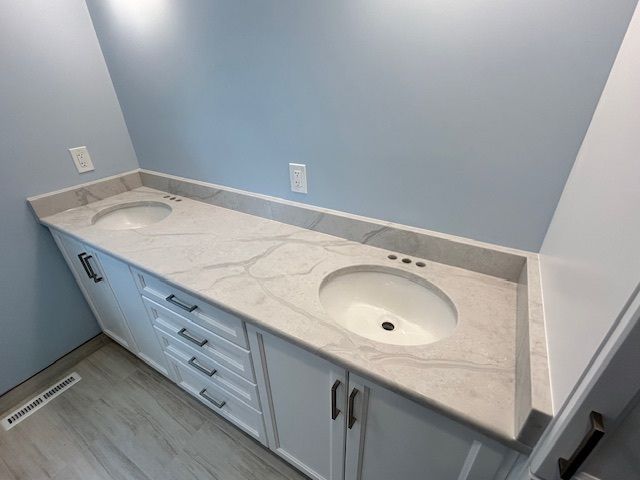 A bathroom with two sinks and white cabinets.