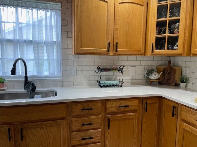 A kitchen with wooden cabinets, a sink, and a window.