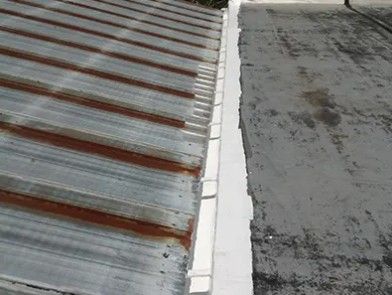 Rusty corrugated metal roof beside a gray flat rooftop with a white seam.