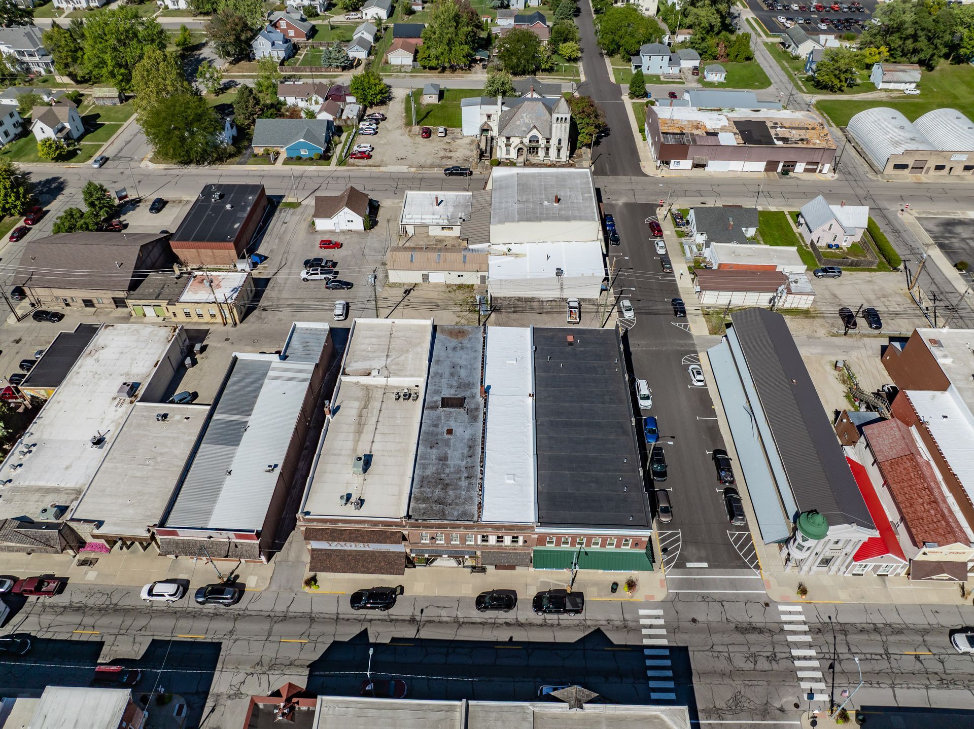 Aerial view of a city block with low-rise buildings, streets, parked cars, and trees
