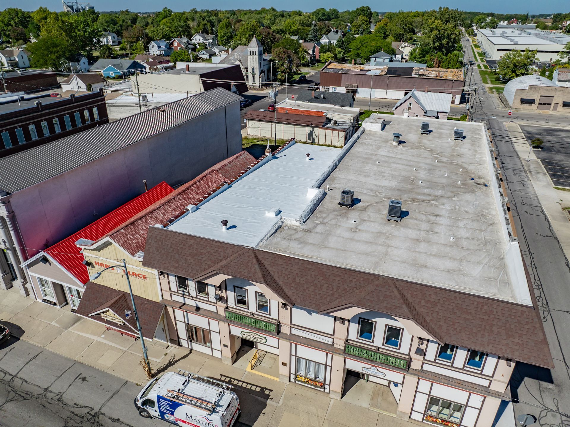 Aerial view of a small downtown block with rooftop HVAC units, adjacent brick buildings, and a mural wall.