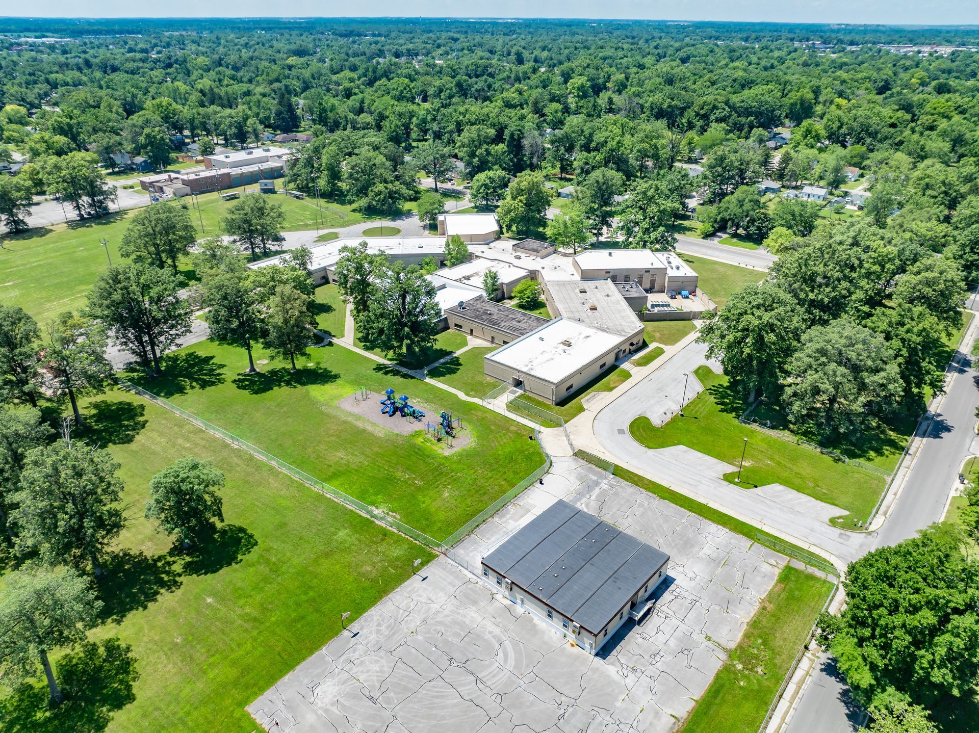 Aerial view of a campus-like building complex surrounded by green trees and lawns.