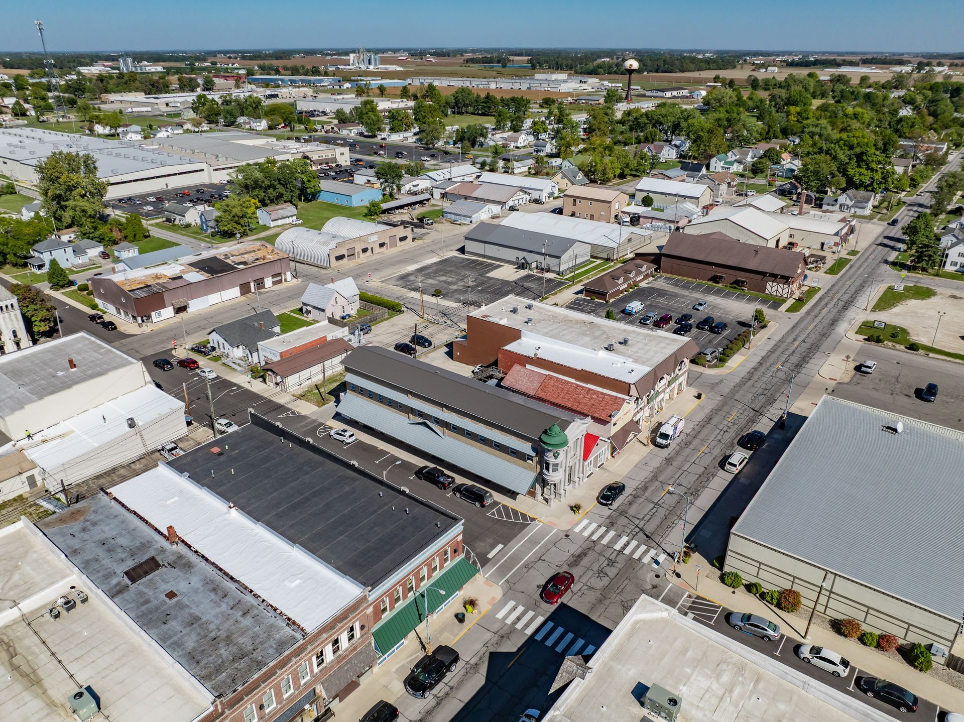 Aerial view of a small downtown with low-rise buildings, streets, parked cars, and palm trees on a sunny day