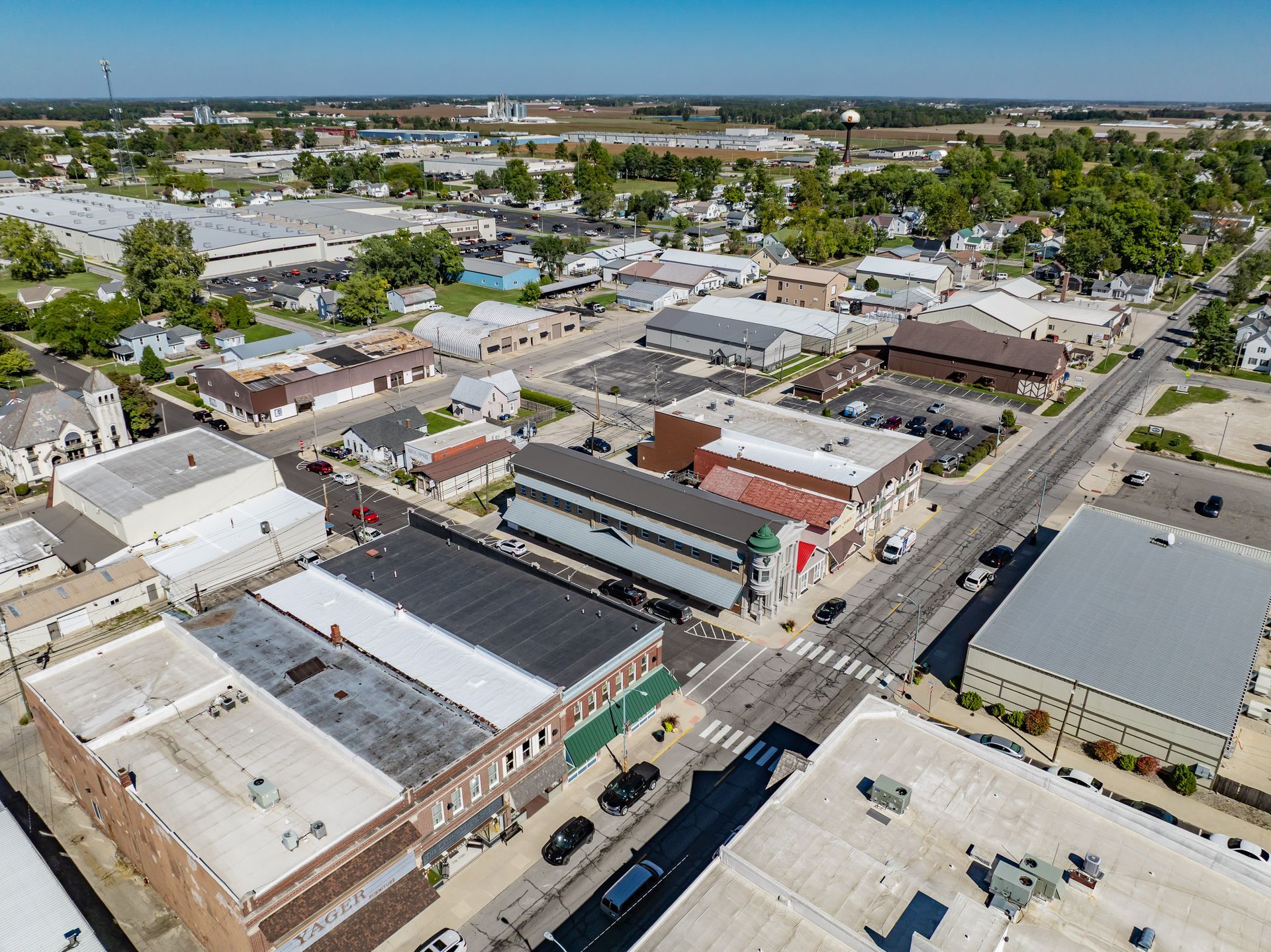 Aerial view of a downtown block with low-rise buildings, streets, and parked cars on a sunny day