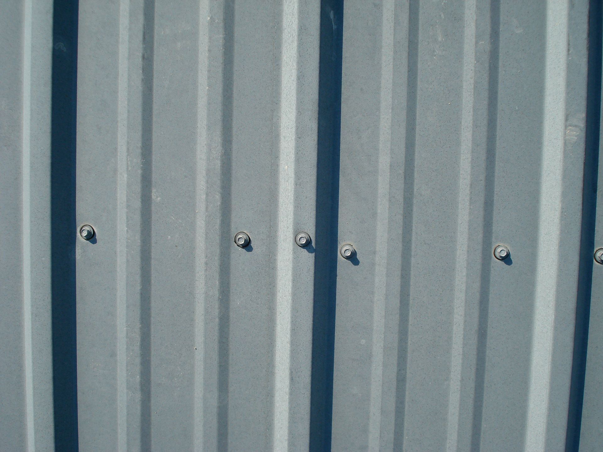 Gray corrugated metal wall with vertical blue support beams and bolts
