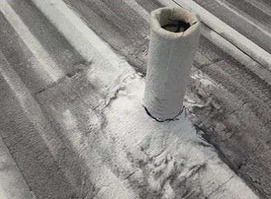 Snow-covered rooftop with a white vent pipe and frost on corrugated metal panels