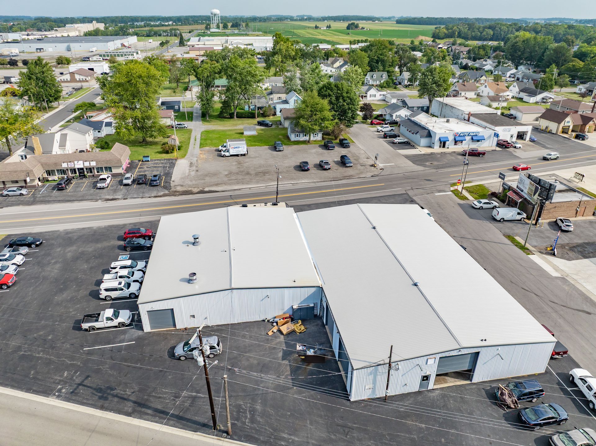 Aerial view of white-roofed industrial buildings with parked cars in a commercial area.