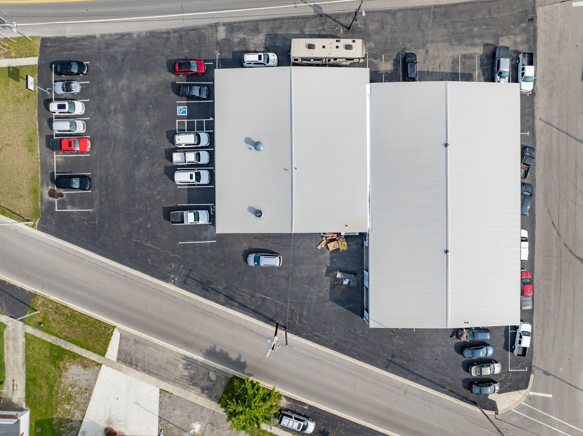 Aerial view of a large industrial building with parked cars and trucks along the lot edges.