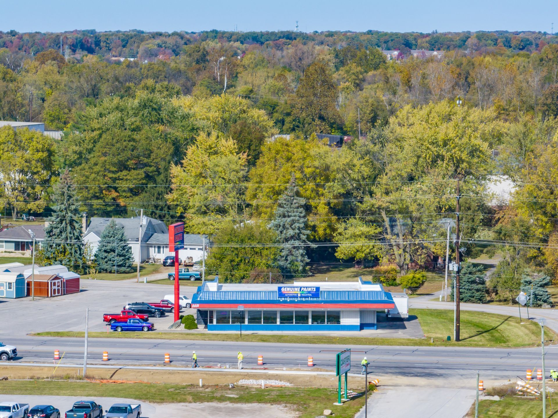 A small roadside restaurant with red roof and parking lot, surrounded by trees in autumn.