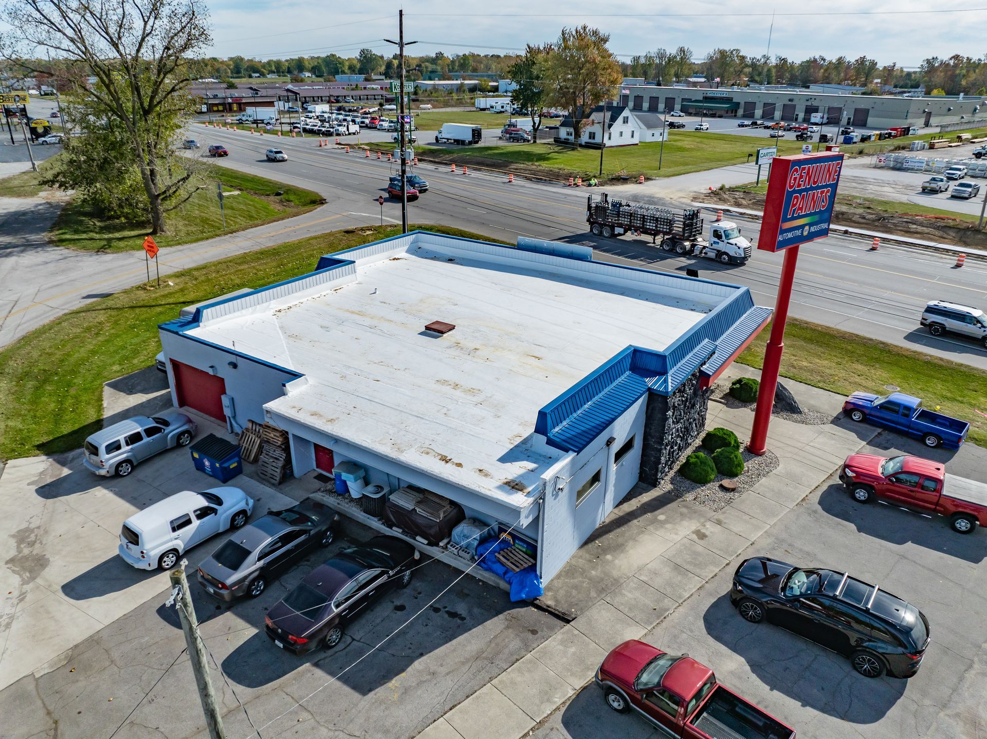 Aerial view of a white-roofed drive-in restaurant with blue trim and a tall red sign beside a parking lot