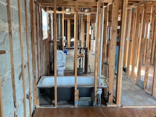 A bathroom in a house under construction with a bathtub and toilet.