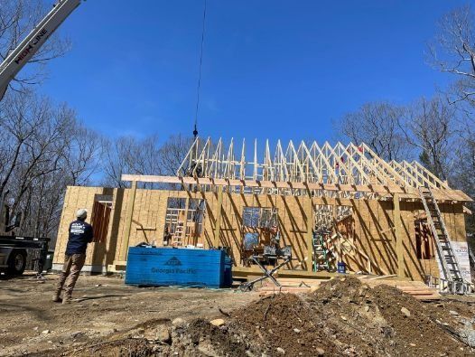 A man is standing in front of a house under construction.